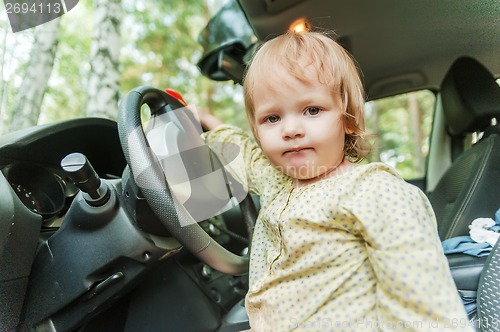 Image of Little blond girl driving car