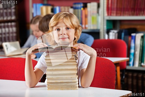 Image of Schoolboy Sitting With Stack Of Books In Library