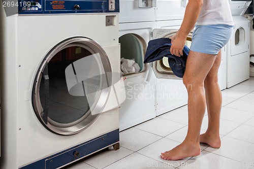 Image of Man Putting Clothes In Washing Machine