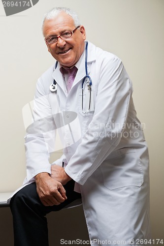 Image of Senior Doctor Sitting On Desk