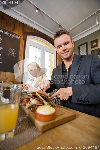 Image of Businessman Having Food With Colleague In Coffeeshop