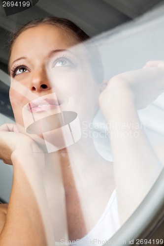 Image of Thoughtful Woman Looking Through Glass Door