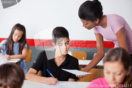 Image of Teacher Showing Paper To Teenage Schoolboy During Examination