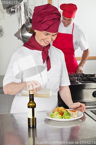 Image of Female Chef Pouring Oil On Dish