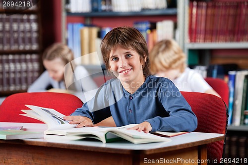 Image of Schoolboy Smiling With Books At Table In Library