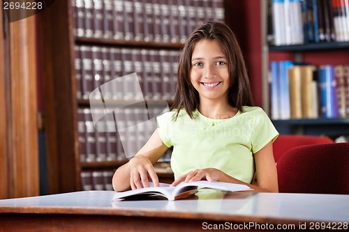 Image of Schoolgirl With Book Sitting At Table In Library