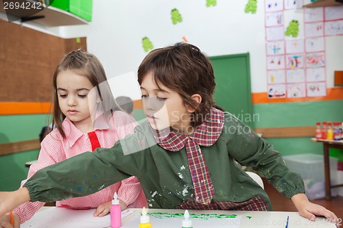 Image of Boy With Girl Painting At Classroom Desk