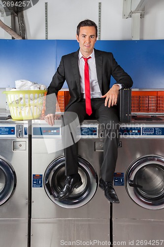 Image of Businessman With Suitcase And Clothes Basket Sitting On Washing