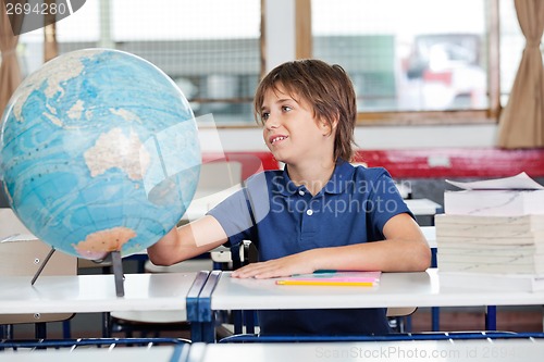 Image of Schoolboy Searching Places On Globe At Desk