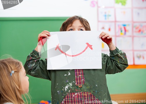 Image of Boy Holding Drawing Paper On Face In Art Class