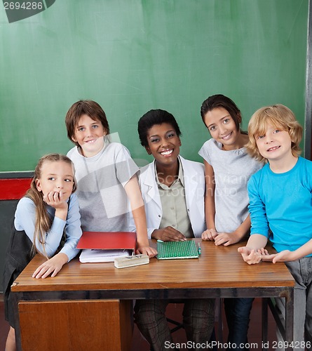 Image of Happy Female Professor With Students At Desk