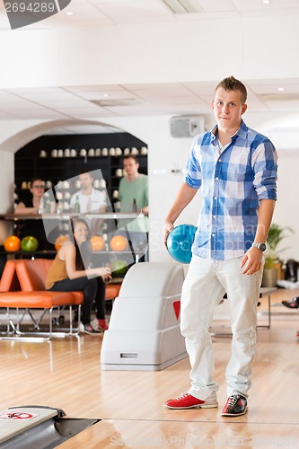 Image of Young Man Holding Bowling Ball in Club