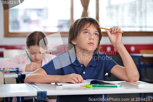 Image of Boy Looking Up While Studying In Classroom