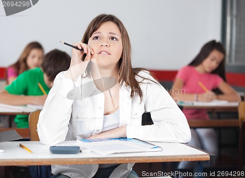 Image of Thoughtful Female Student Looking Up At Desk