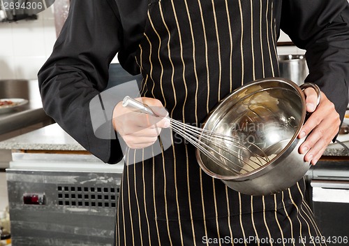 Image of Male Chef Whisking Egg In Kitchen