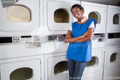 Image of Female Helper Leaning On Dryers In Laundry