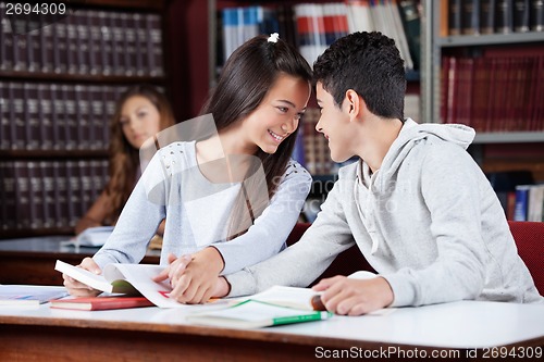 Image of Loving Teenage Couple Holding Hands At Table In Library