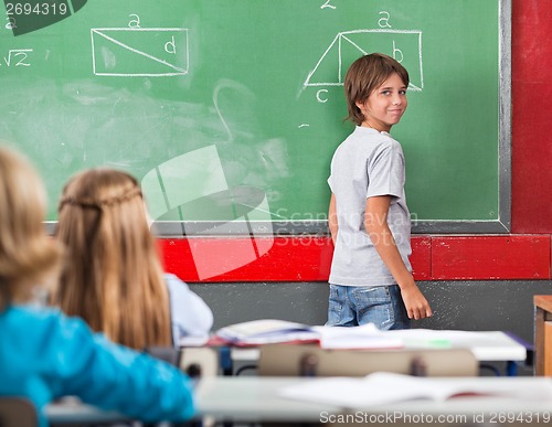 Image of Little Boy Standing By Board In Classroom