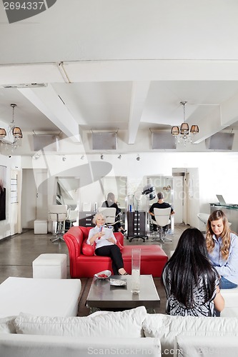 Image of Client Having Manicure With People Waiting In Salon