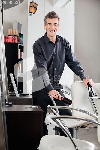Image of Happy Hairstylist Holding Straightener And Brush