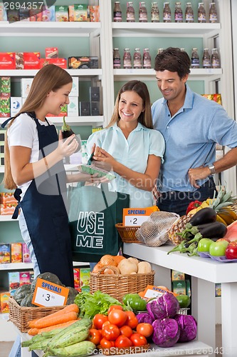 Image of Saleswoman Showing Vegetable Packet To Couple
