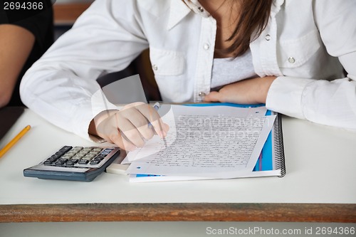 Image of Schoolgirl With Calculator; Paper And Book At Desk