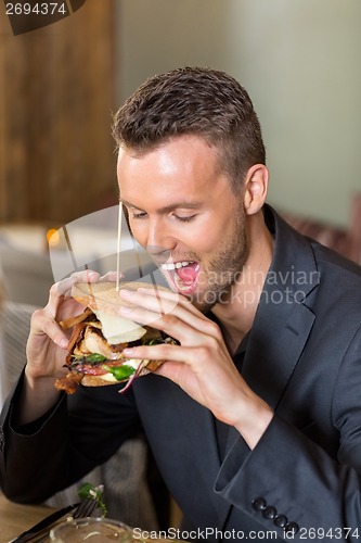 Image of Young Businessman Eating Sandwich