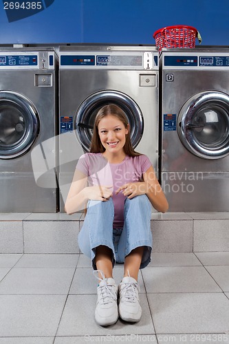 Image of Woman Sitting Against Washing Machines At Laundry