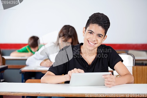 Image of Male University Student Using Digital Tablet At Desk