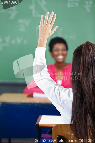 Image of Teenage Girl Raising Hand At Desk