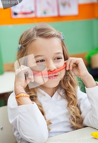 Image of Girl Holding Mustache Made Of Clay In Classroom