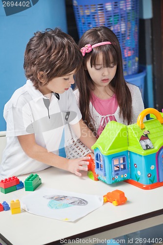 Image of Boy And Girl Playing With Plastic House In Kindergarten