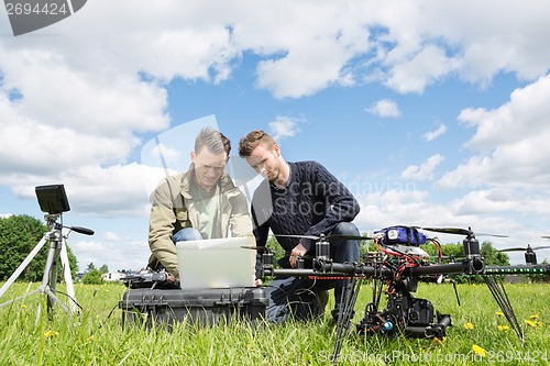 Image of Technicians Working On Laptop By UAV in Park