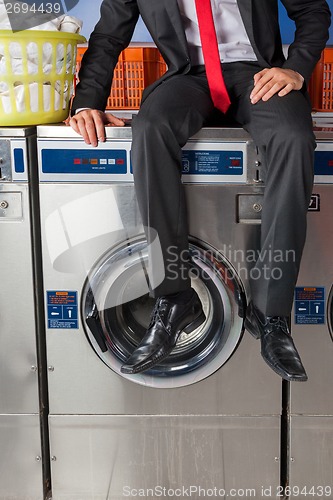 Image of Businessman Sitting On Washing Machine