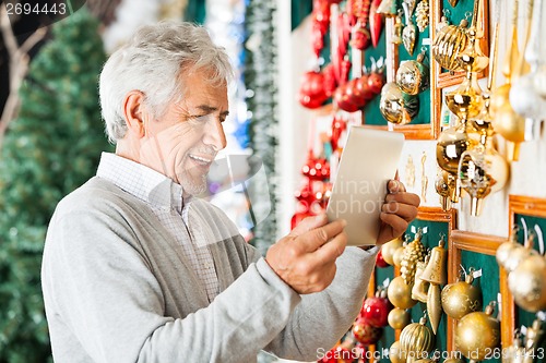 Image of Happy Man Photographing Christmas Ornaments At Store