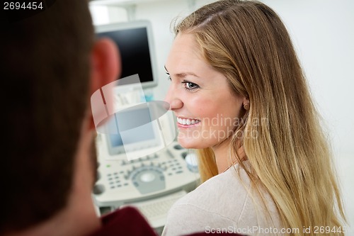 Image of Woman Looking At Man With Ultrasound Machine In Background