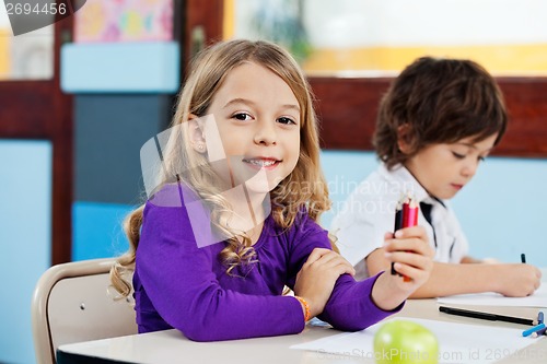 Image of Girl Holding Color Pencils With Friend Drawing In Background