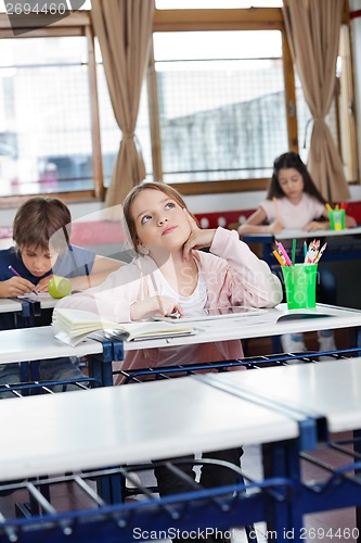 Image of Schoolgirl Looking Up With Digital Tablet At Desk