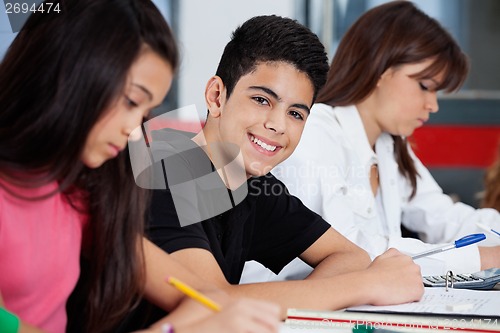 Image of Schoolboy Sitting With Female Friends At Desk