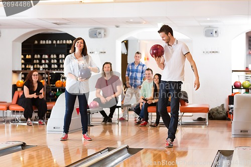 Image of Man And Woman Holding Bowling Balls in Club