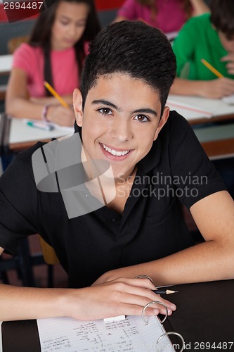 Image of High School Student Smiling While Sitting At Desk