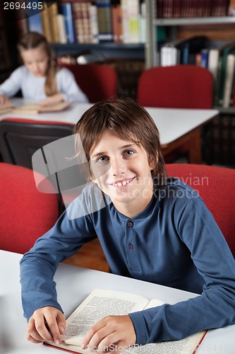 Image of Schoolboy With Book Sitting In Library