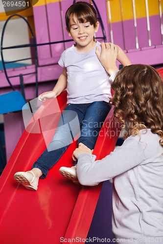 Image of Teacher Assisting Girl While Playing On Slide