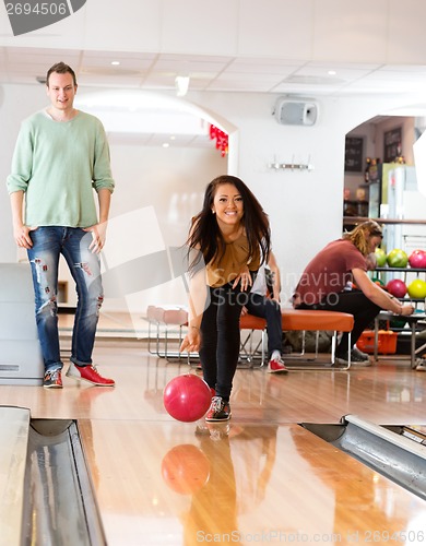 Image of Happy Young Woman Bowling in Club