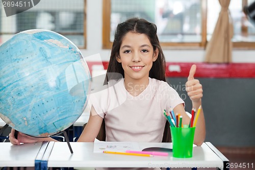 Image of Schoolgirl Gesturing Thumbs Up At Desk