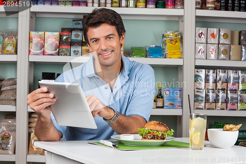 Image of Male Customer With Snacks Using Digital Tablet In Supermarket