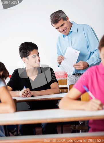 Image of Teacher And Teenage Schoolboy Looking At Paper