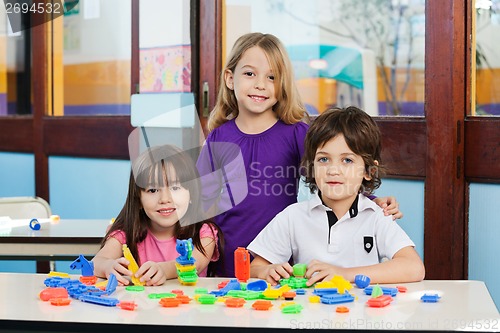 Image of Cute Friends With Blocks On Desk In Classroom