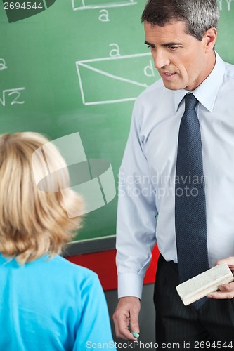 Image of Teacher With Duster And Chalk Looking At Boy