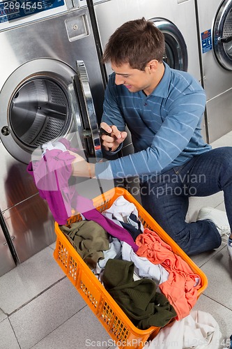 Image of Man Putting Clothes In Washing Machine